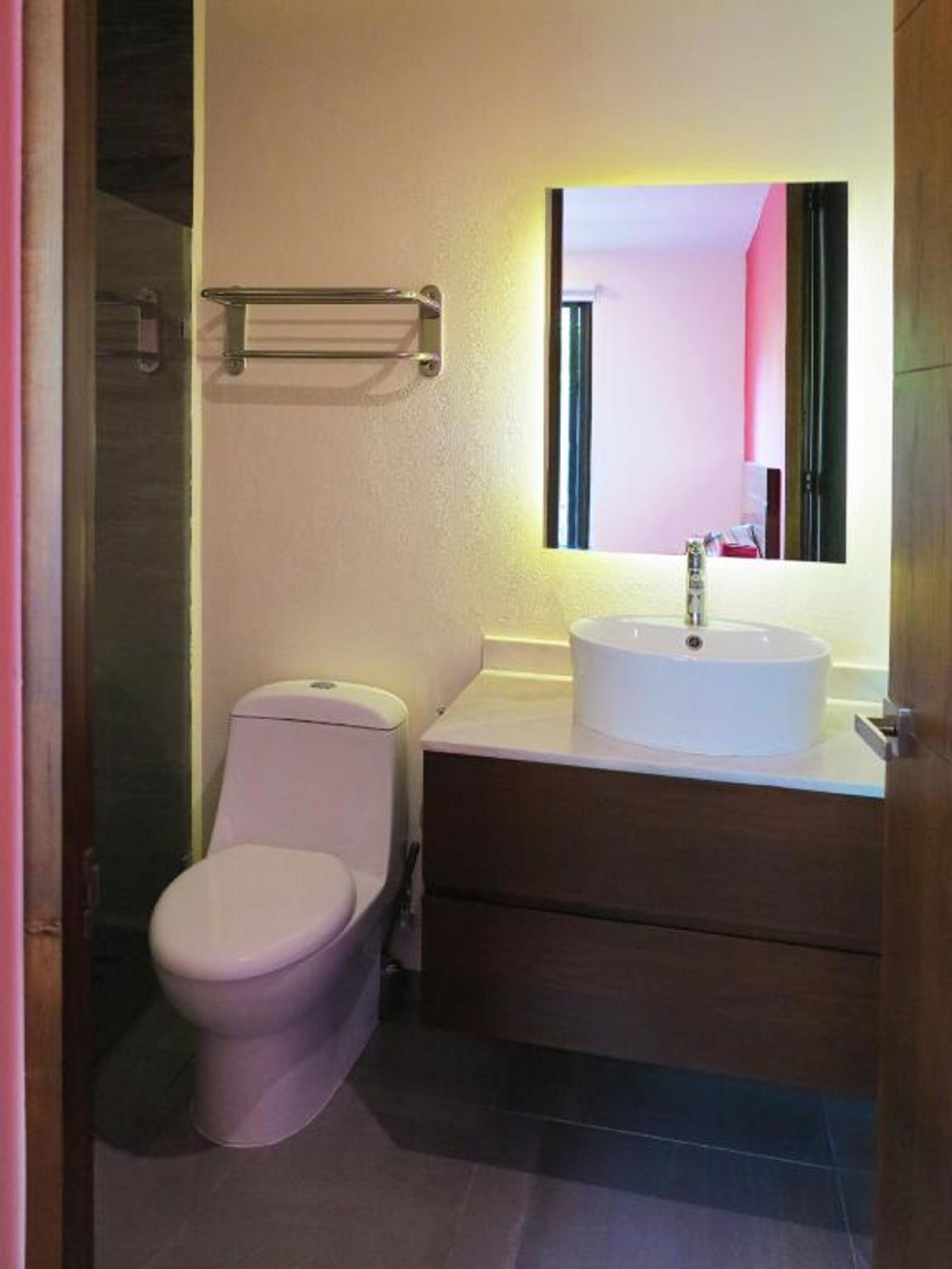 A small bathroom with a toilet, a sink, and a mirror.