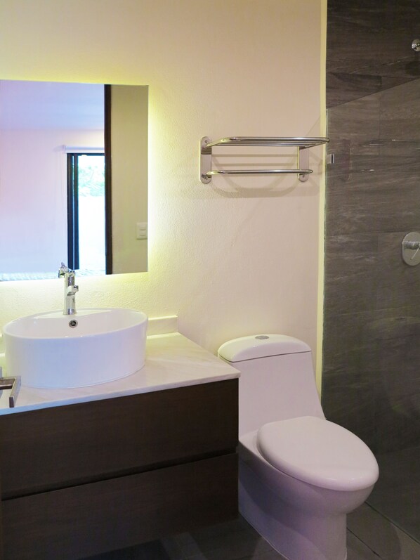 Une salle de bain moderne avec un lavabo blanc, un miroir et des toilettes.