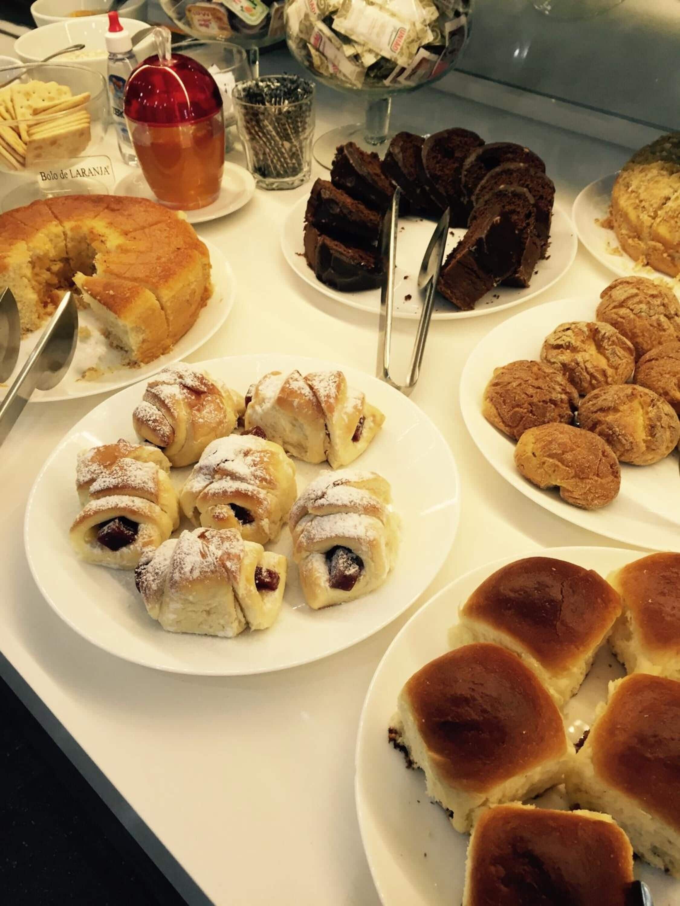 Une variété de pâtisseries et de desserts étaient disposés sur une table de buffet, notamment un gâteau, des parts de chocolat et différents types de petits pains.