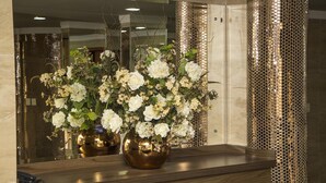 A reception area with a wooden reception desk, a large mirror, and a decorative wall with a honeycomb pattern. - JP Palace Hotel (Franca)