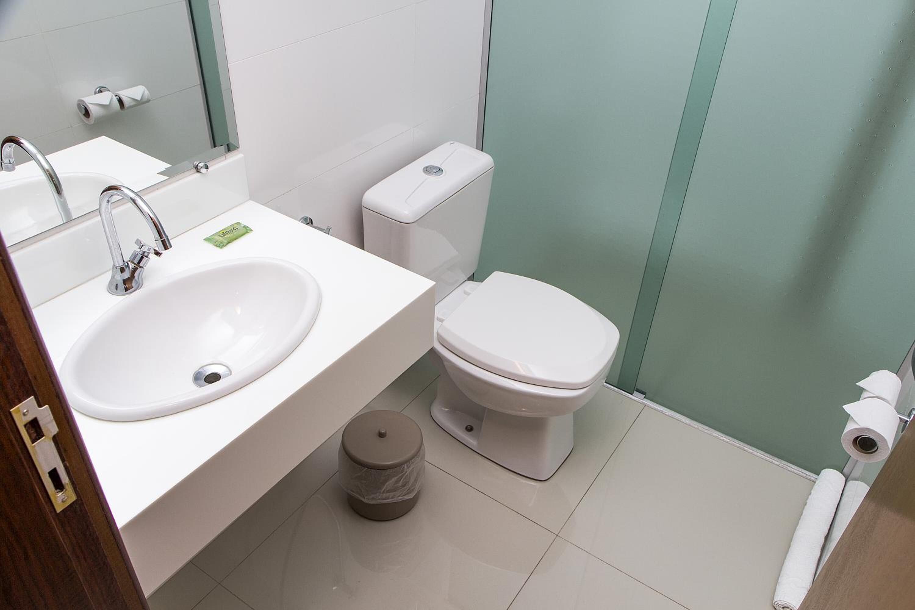 Un baño moderno con un lavamanos blanco, un inodoro y un cubo de basura.