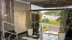 A modern hotel lobby with a checkered floor, metal railings, and potted plants. - JP Palace Hotel (Franca)