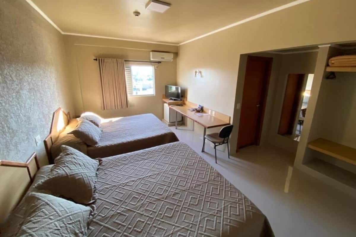 Een hotelkamer met twee bedden, een bureau, een stoel en een televisie.