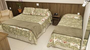 A hotel room with two beds, a chair, a bedside table, a lamp, and a potted plant.