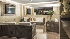 A modern lobby with a reception desk, seating area with sofas and chairs, and a large flat-screen TV mounted on the wall. - JP Palace Hotel (Franca)