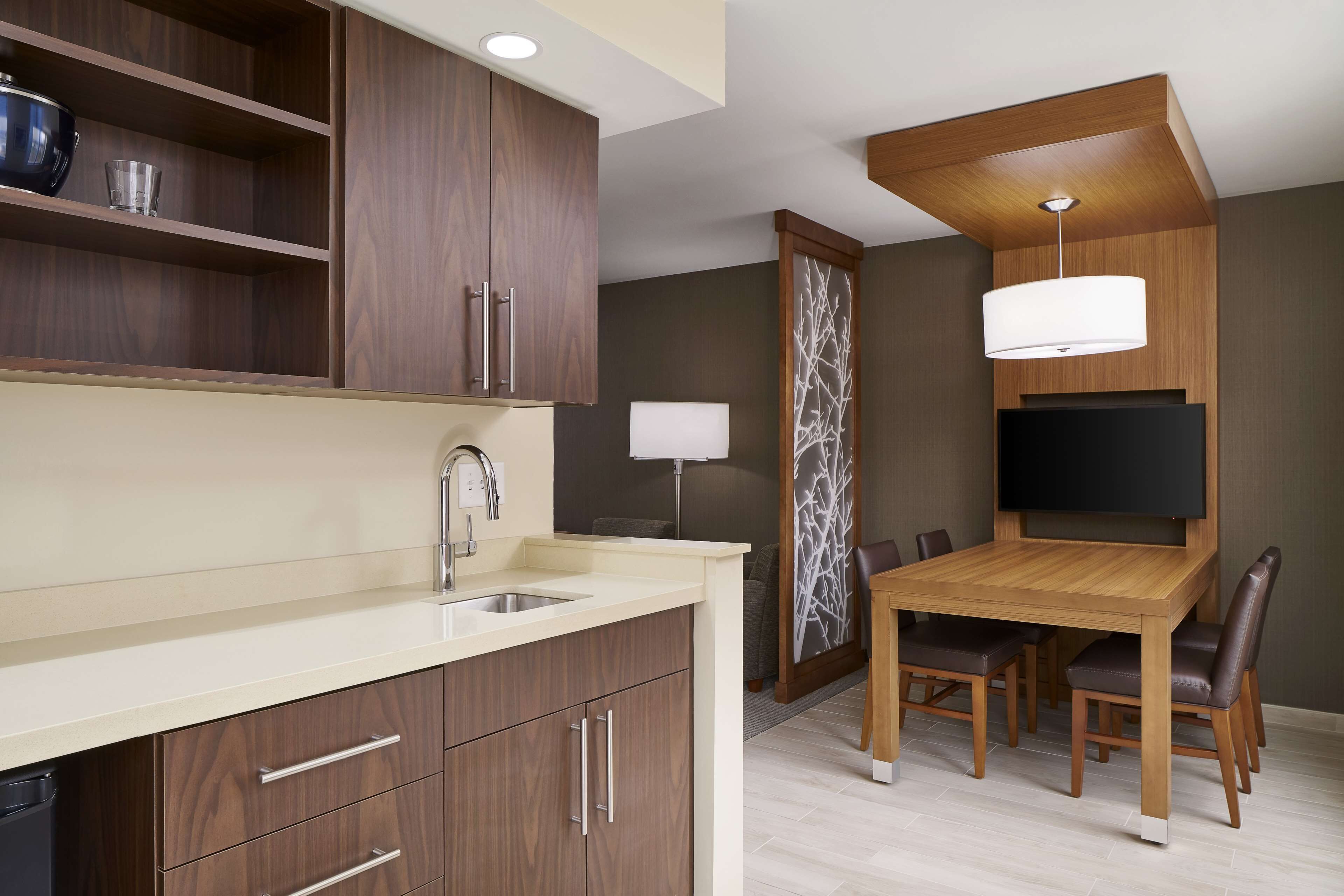 A modern kitchen with wooden cabinets, a built-in sink, and a dining area with a wooden table and chairs.