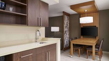 A modern kitchen with wooden cabinets, a built-in sink, and a dining area with a wooden table and chairs.