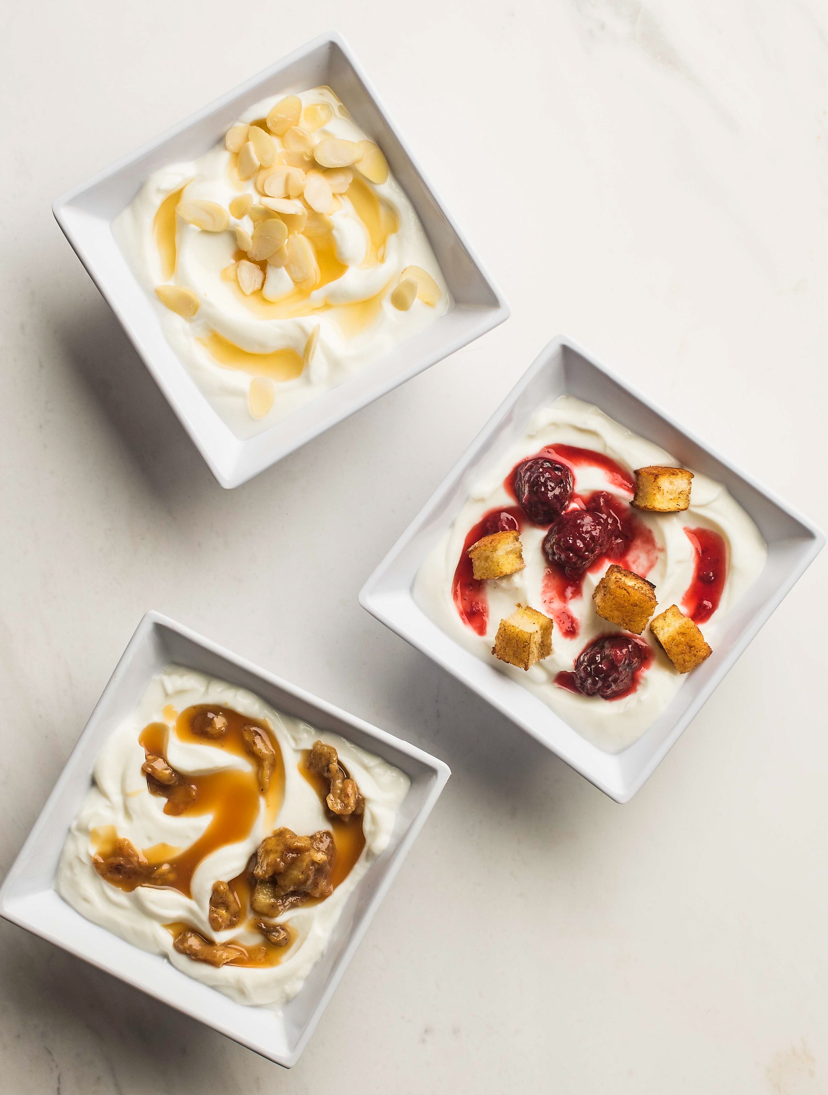 Three bowls of yogurt with different toppings.