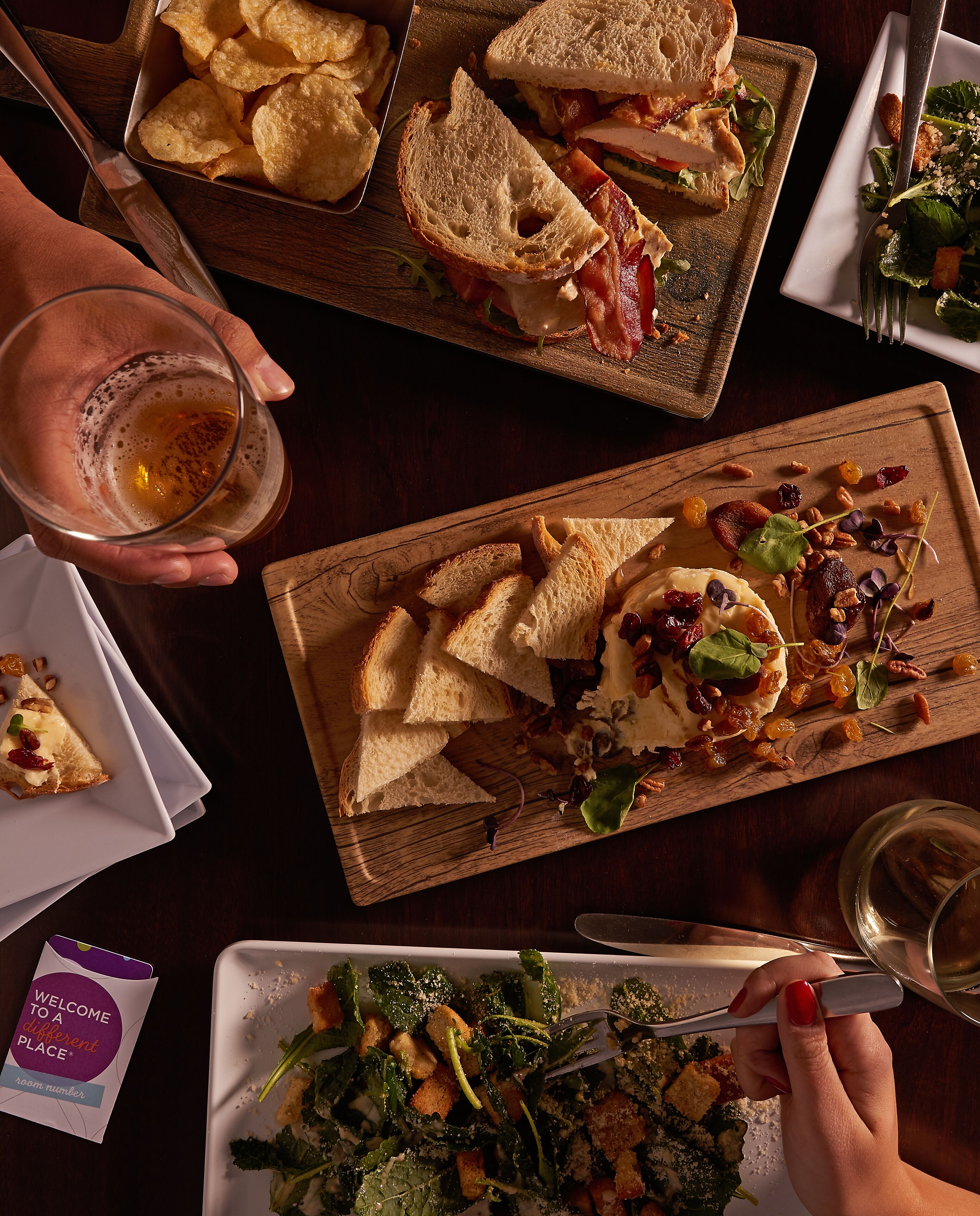 Une table à manger avec divers aliments, notamment des sandwichs, des chips et une salade.
