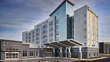 A modern hotel with a glass facade, a covered entrance, and signage for 'Riverfront Events' and 'Hyatt Place'.
