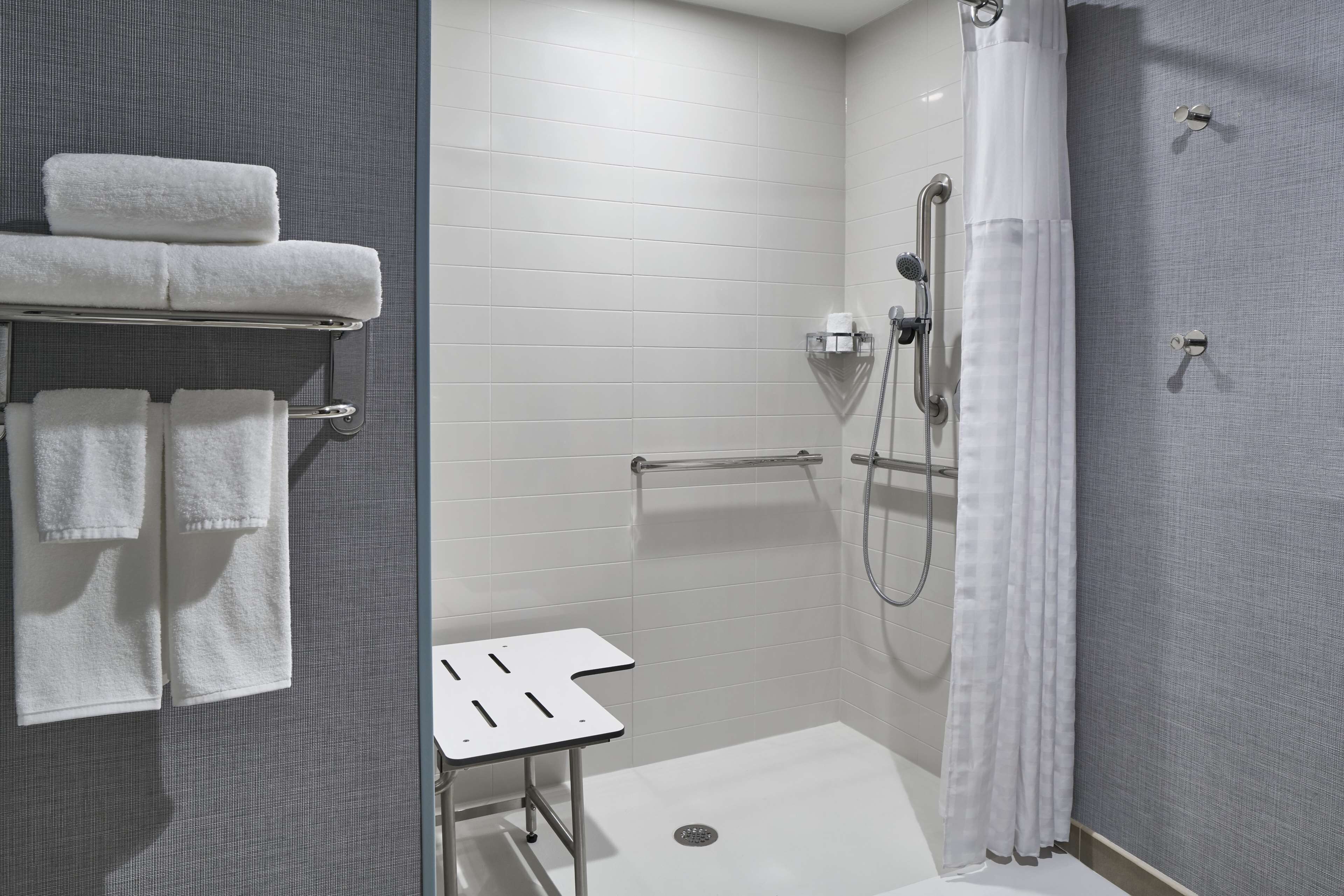 Un baño moderno con ducha, toallero y una mesita.