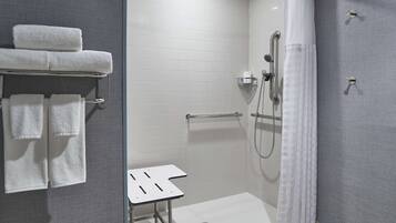 Un baño moderno con ducha, toallero y una mesita.