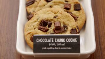 Un plat rectangular blanc amb galetes de xocolata i un etiquetatge que diu "Chocolate Chunk Cookie".