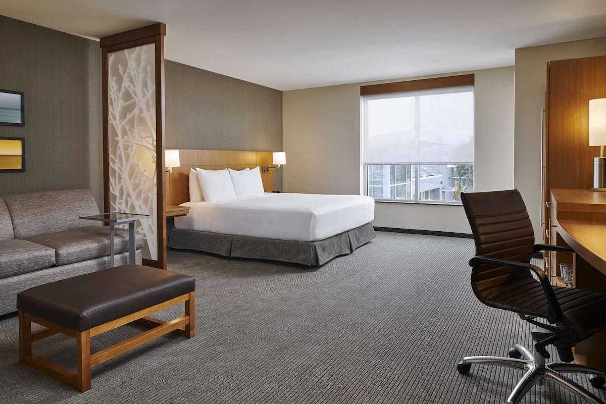 Une chambre d’hôtel comprenant un lit, un bureau, une chaise, un canapé et une petite table.