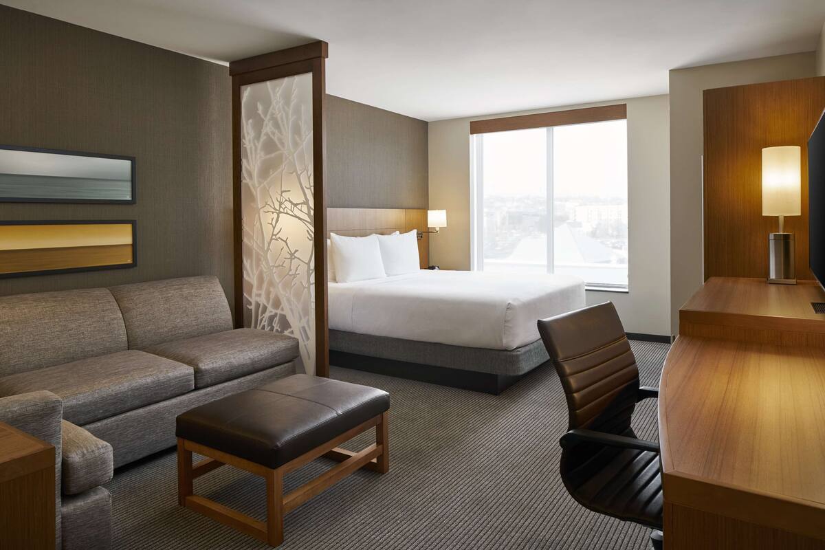 Une chambre d’hôtel avec un lit, un canapé, un bureau et une chaise.