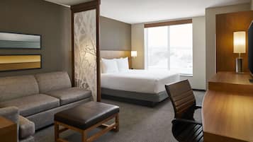 Quarto de hotel com cama, sofá, escrivaninha e cadeira.