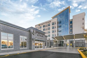 Ein Hotel mit modernem Design, dessen Eingang durch eine Glasfassade und einen überdachten Bereich gekennzeichnet ist.