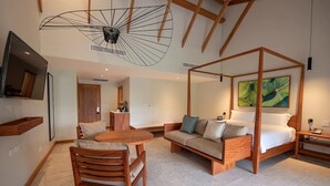 A modern bedroom with a four-poster bed, a sofa, a dining table with chairs, and a TV mounted on the wall. - Tabacon Thermal Resort AND SPA (La Fortuna)