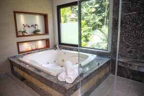 A modern bathroom with a large freestanding bathtub, a glass shower enclosure, and a view of lush greenery outside. - Tabacon Thermal Resort AND SPA (La Fortuna)