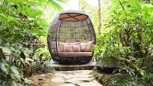 A wicker swing chair with cushions in a lush garden setting. - Tabacon Thermal Resort AND SPA (La Fortuna)