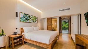 A modern bedroom with a wooden bed, a bedside table with a lamp, a wall-mounted artwork, and a view of a green outdoor area. - Tabacon Thermal Resort AND SPA (La Fortuna)