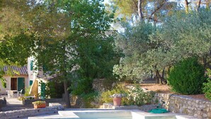 A pool area with stone walls, potted plants, and a stone building in the background. - Authentic farmhouse in Saint Remy de Provence (Saint-Rémy-de-Provence)