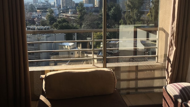 A room with a large window offering a view of a cityscape and mountains. - Amistar Apartments (Santiago)