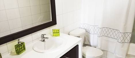 A bathroom with a white sink, a mirror, a toilet, and a shower curtain.