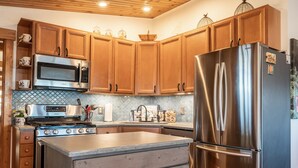 A kitchen with wooden cabinets, stainless steel appliances, and a tiled backsplash. - Minutes to Galena.  Bird Cottage @ Sorriso Vineyard Galena Illinois (Galena)