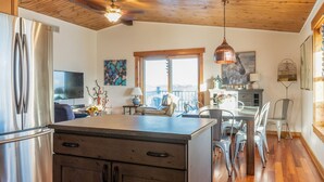 A modern kitchen with wooden ceiling beams, stainless steel appliances, and a dining area with metal chairs and a table. - Minutes to Galena.  Bird Cottage @ Sorriso Vineyard Galena Illinois (Galena)
