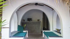 A room with a ceiling fan, a TV, and two seating areas with cushions.