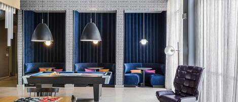 Un área de lounge moderna con mesa de billar, cómodos asientos y espacio para jugar al billar.