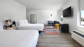 Una habitación de hotel moderna con dos camas, un escritorio, una silla, un televisor y un ventanal grande.
