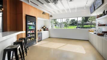 A modern bar area with stools, a refrigerator stocked with beverages, and a view of the outdoors.