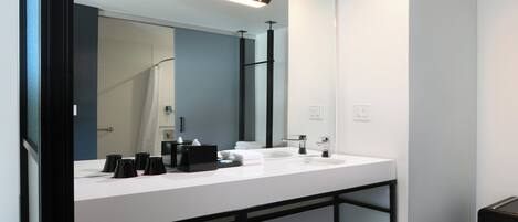 A modern bathroom with a large mirror, two sinks, and a black vanity.