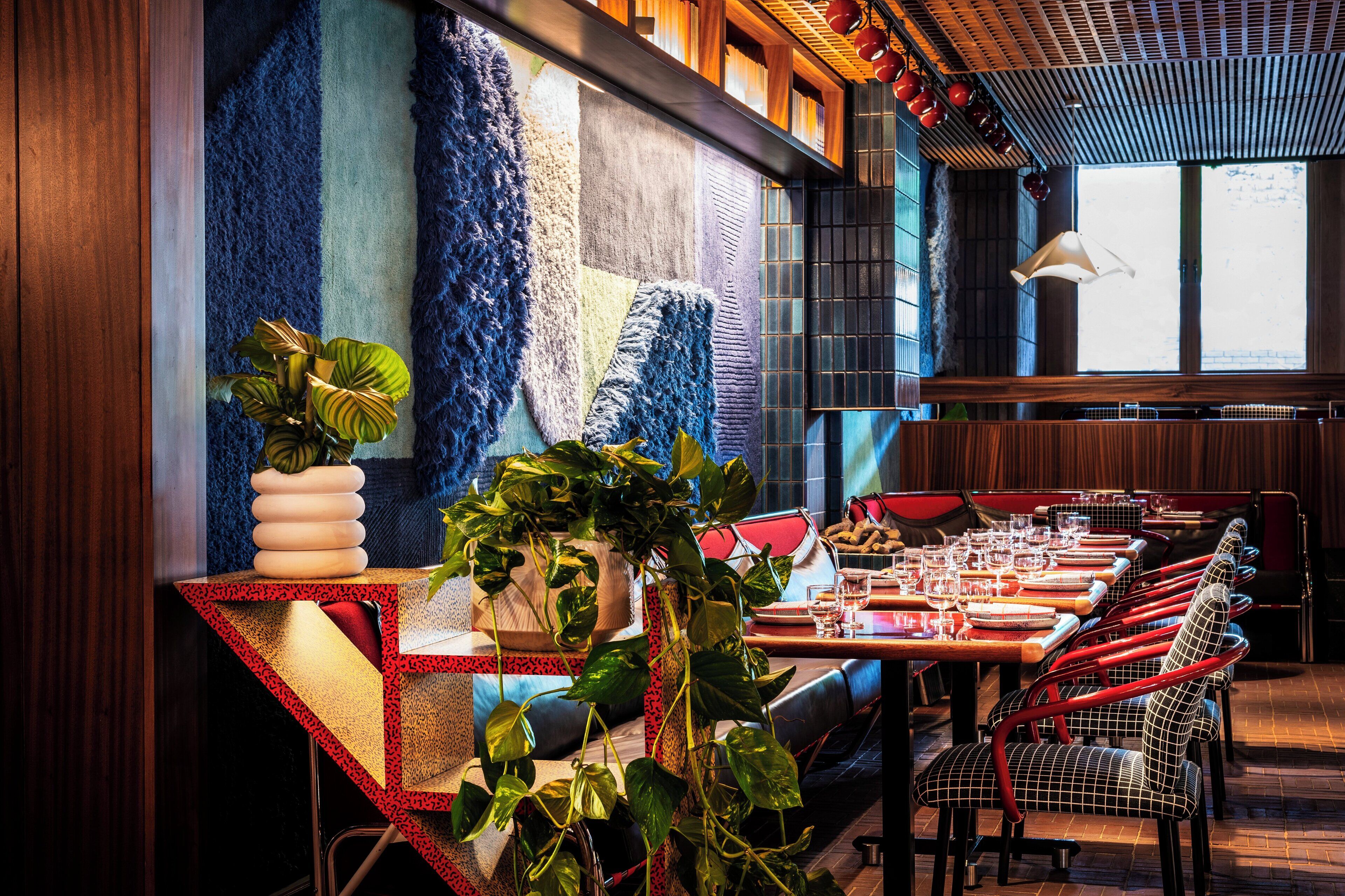 Un restaurante con una larga mesa de comedor, sillas rojas y una variedad de plantas.