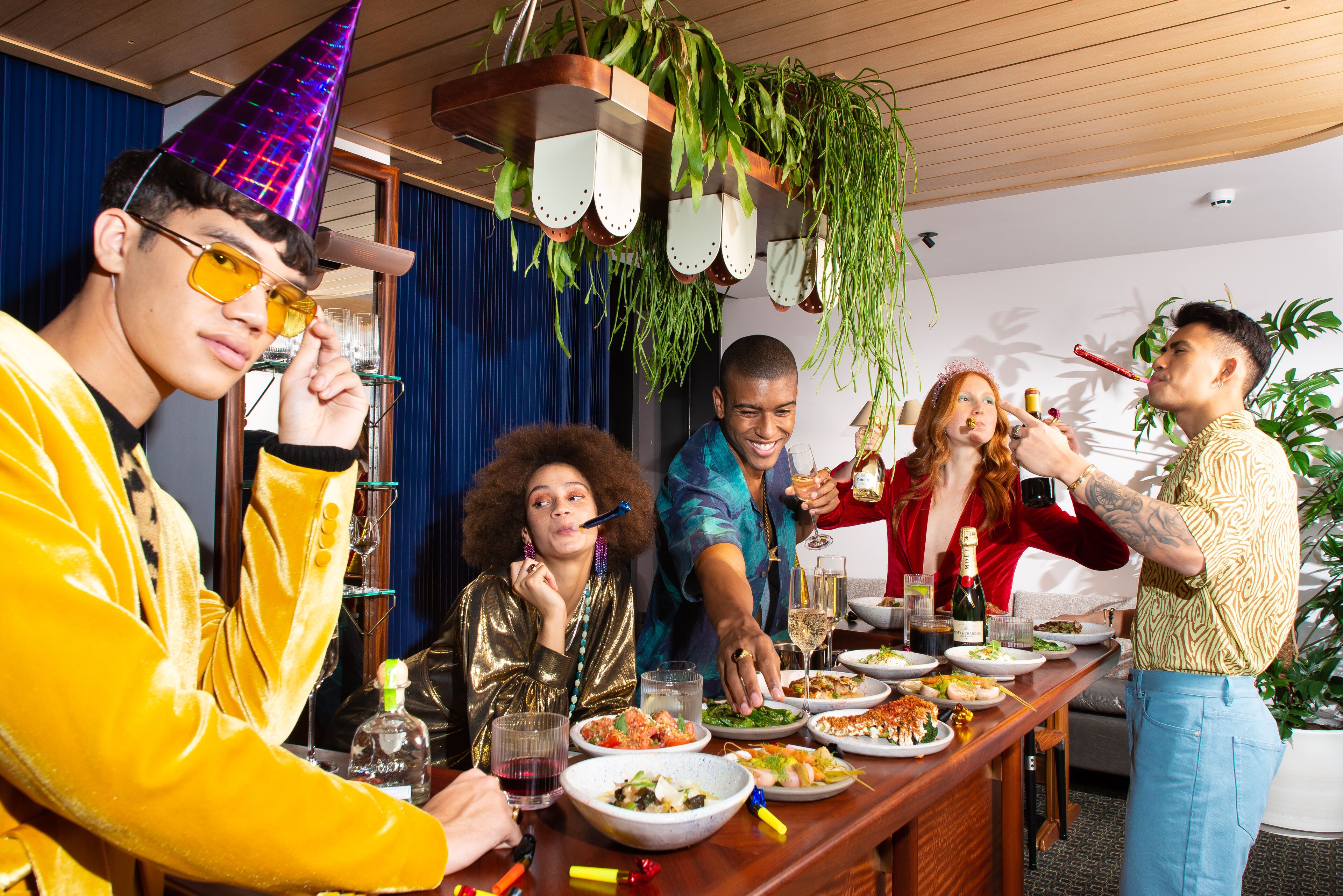A group of people dining at a wooden bar with various dishes and drinks.