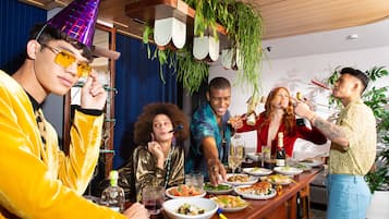 A group of people dining at a wooden bar with various dishes and drinks.