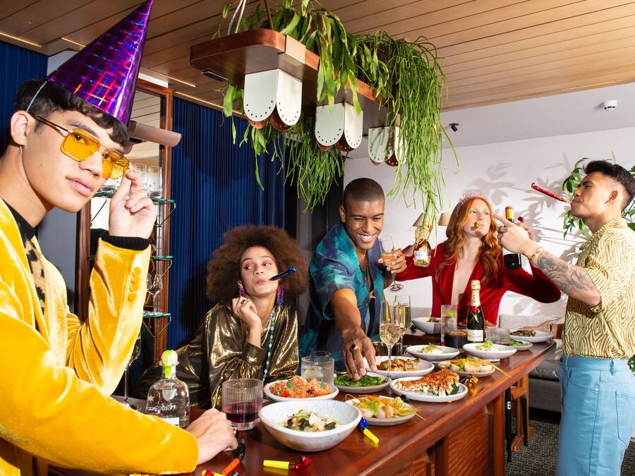 A group of people dining at a wooden bar with various dishes and drinks.