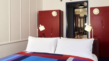 Una habitación de hotel con una cama grande, dos lámparas de noche, un armario rojo y un espejo.