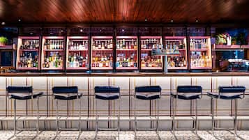 A bar area with multiple shelves of bottles, bar stools, and a patterned floor.