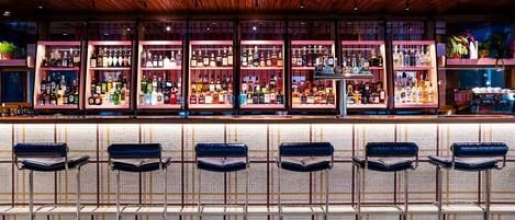 A bar area with multiple shelves of bottles, bar stools, and a patterned floor.