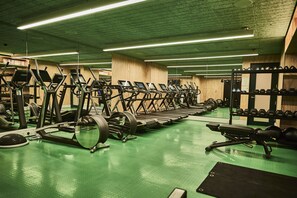 A gym with treadmills, weight machines, and dumbbells.