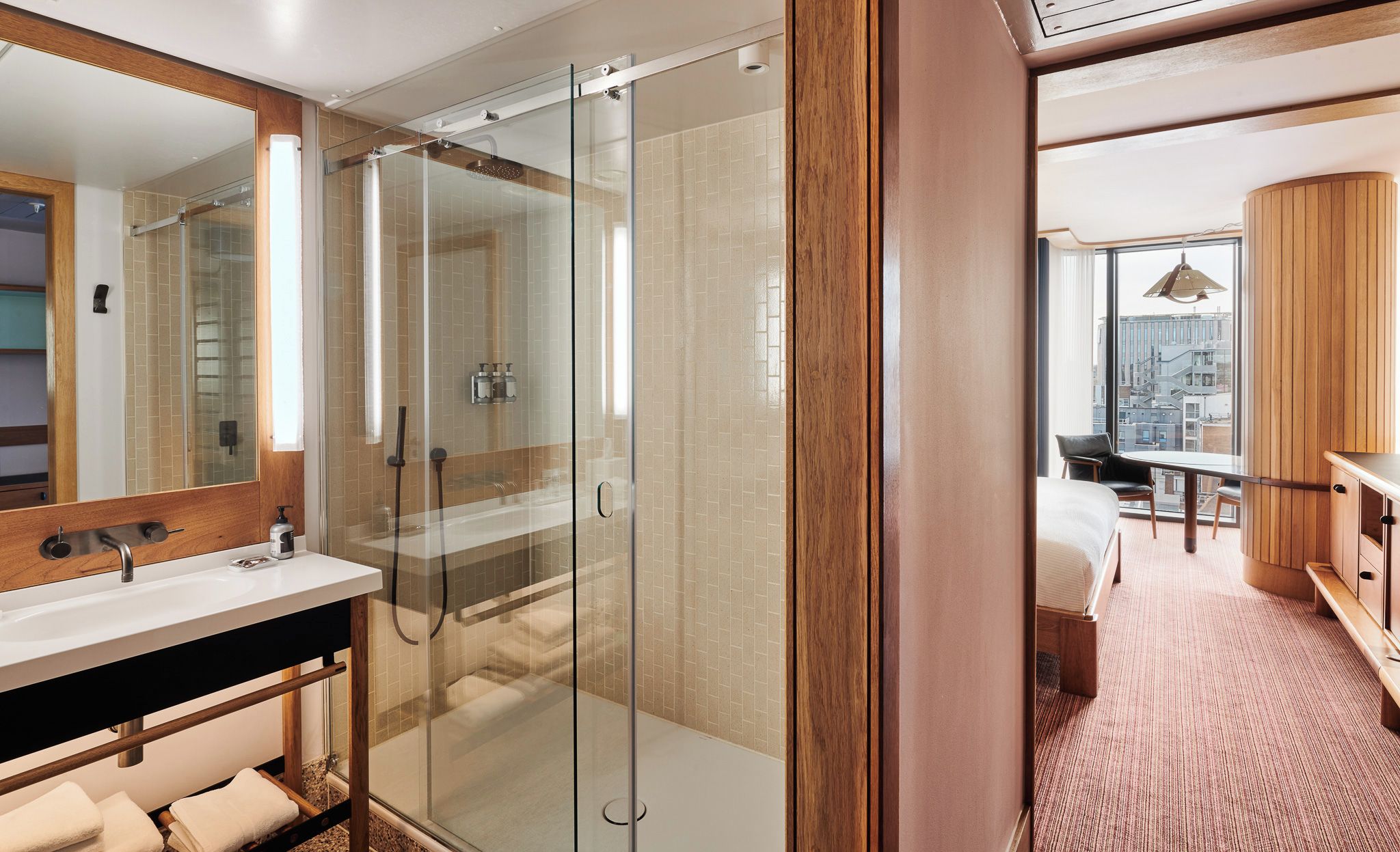 Un baño moderno con ducha de vidrio, tocador de madera y un espejo grande.