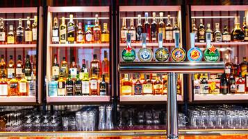 Un bar con varias botellas de licor y una grifería con diferentes marcas de cerveza.