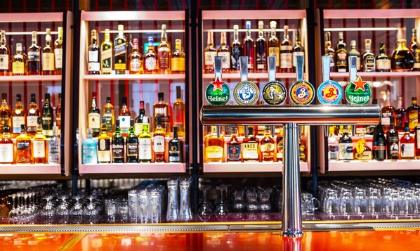 A bar with multiple liquor bottles and a tap with various beer brands.