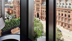 Ein Zimmer mit großen Fenstern und Blick auf ein historisches Gebäude mit mehreren Türmen und einem Innenhof.