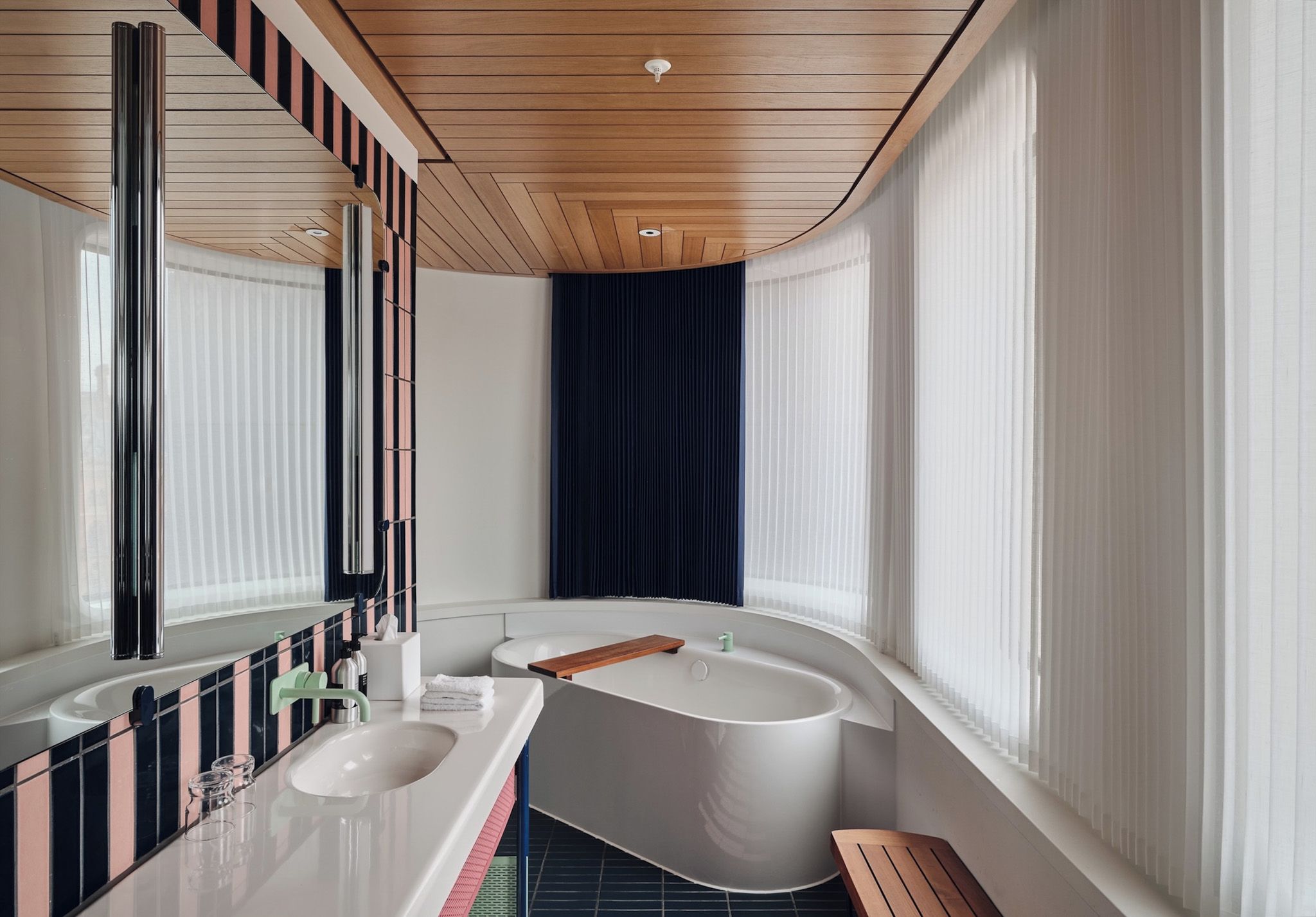 Un baño moderno con una bañera independiente, un espejo grande y un tocador con lavabo.