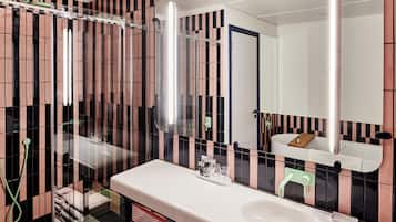 A bathroom with a white sink, a mirror, and a shower area.