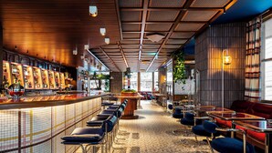 Eine Bar mit gefliestem Boden, Barhocker und einer Theke, auf der verschiedene Flaschen präsentiert werden.